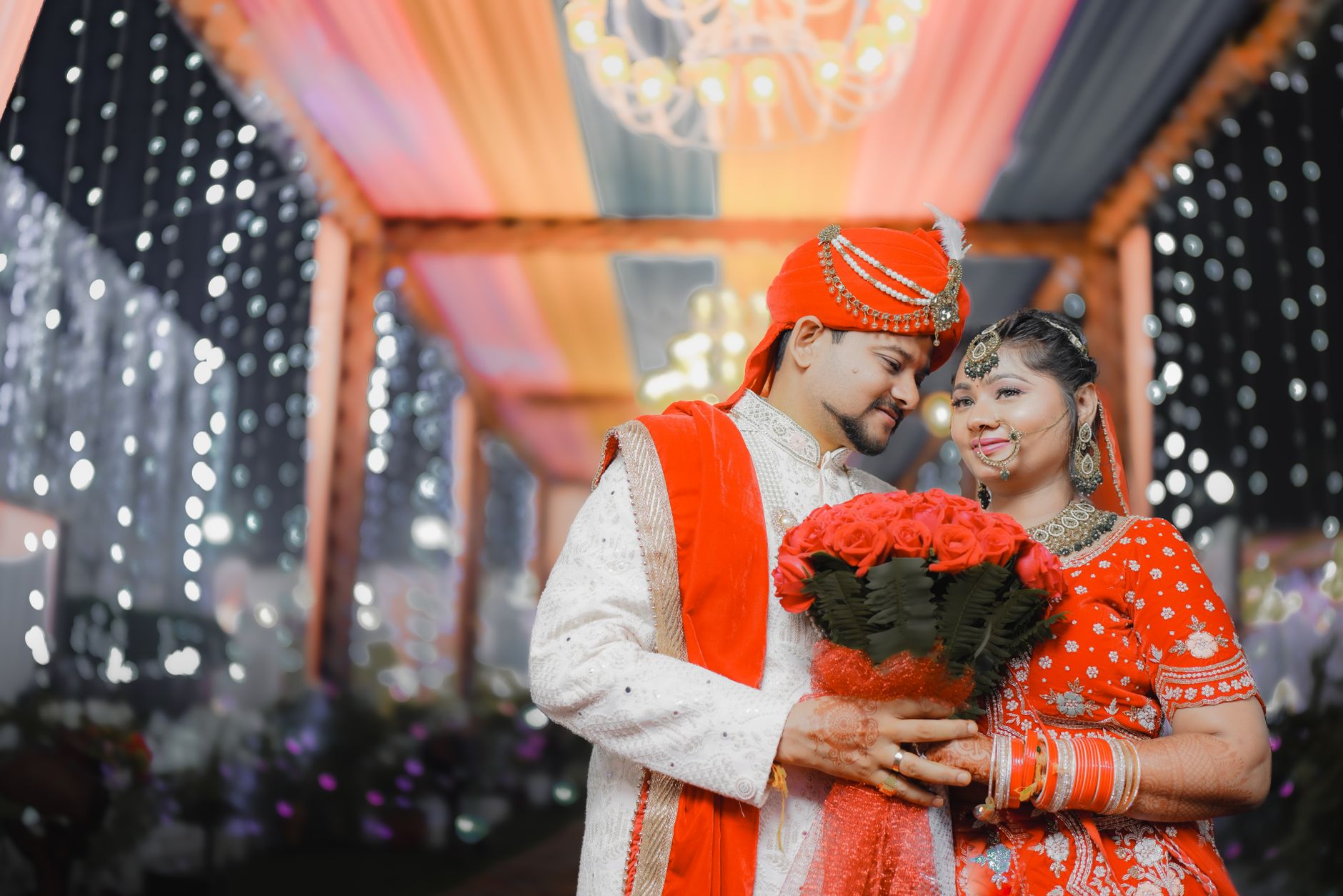 A beautiful South Asian couple celebrating their wedding under a decorated mandap.